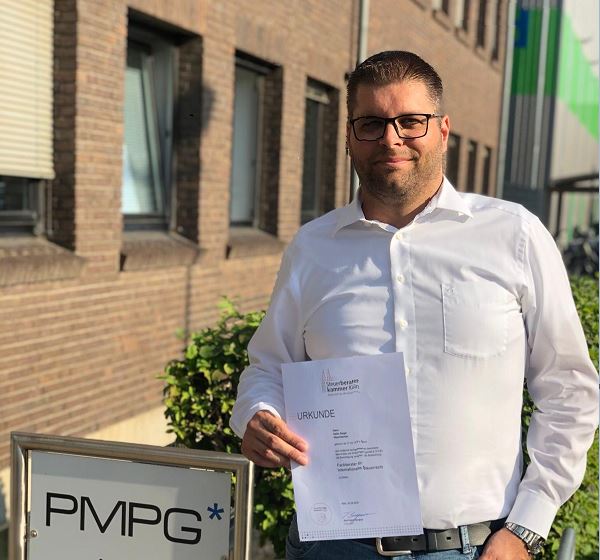 PMPG-Steuerberater Heiko Sieger steht vor dem Gebäude und hält Urkunde zum Fachberater für Internationales Steuerrecht
