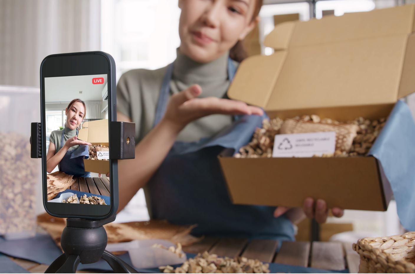 Weibliche Influencerin hält ein Produkt im Karton vor ihre Handykamera